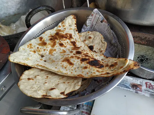Naan bread being baked inside a traditional Indian tandoor oven.