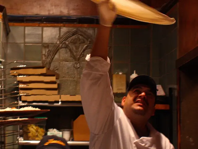 Pizza dough being tossed and stretched by hand at a restaurant.