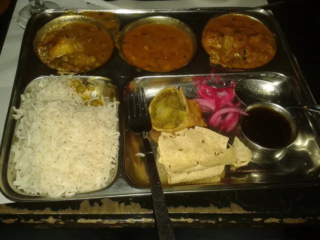 A mixed Indian thali plate with rice, bread, and several curries.