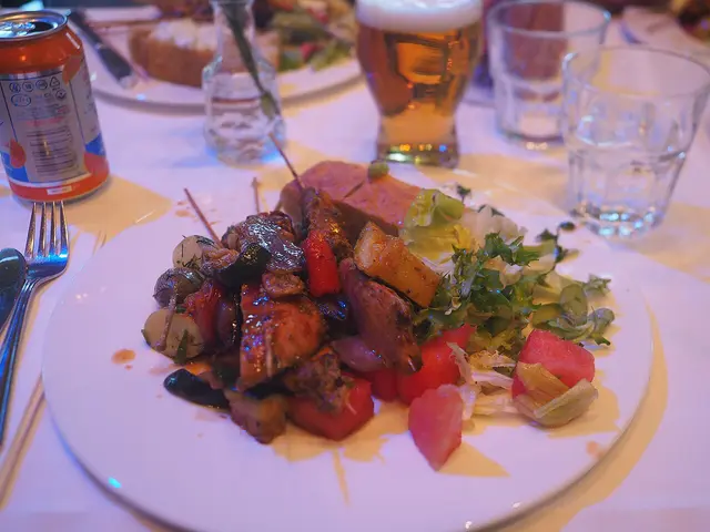 A plate of food from a restaurant dinner buffet next to a glass of beverage.