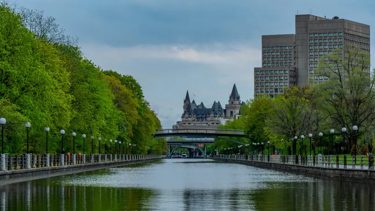 The Rideau Canal in Ottawa lined with trees, with the Château Laurier in the distance